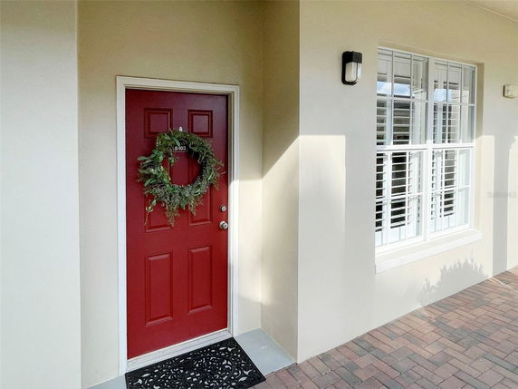 Front view of a house entrance with a red door and a decorative wreath.