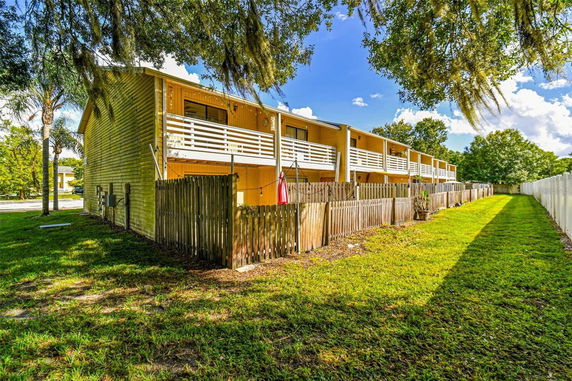 Front view of a two-story row of townhouses with balconies and fenced-in areas.