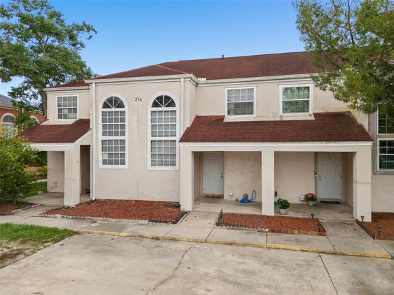 Front view of a two-story townhouse with arched windows and a red roof.