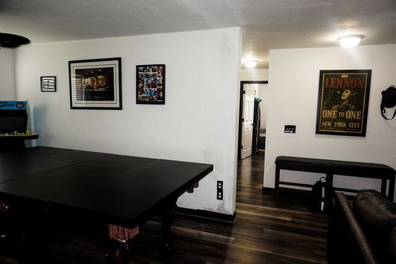 Room with a pool table and framed posters on the wall.