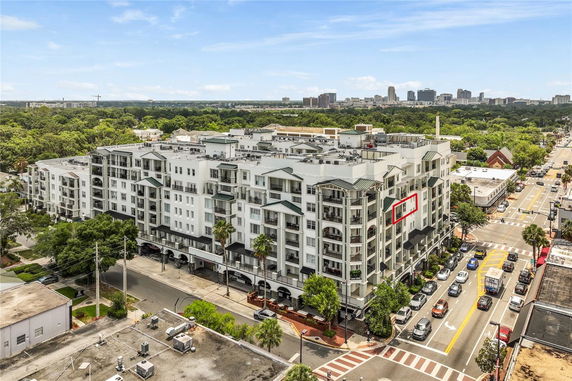 Front view of a multi-story residential building in an urban setting with balconies and a rooftop.