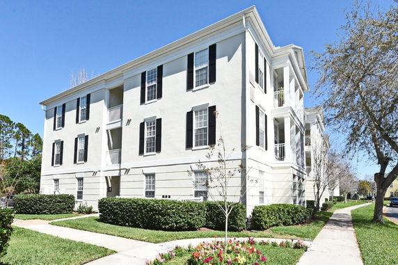 Front view of a three-story residential building with black shutters and balconies.