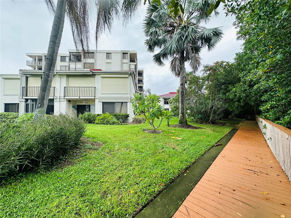 Front view of a multi-story building with balconies and surrounding green lawn.