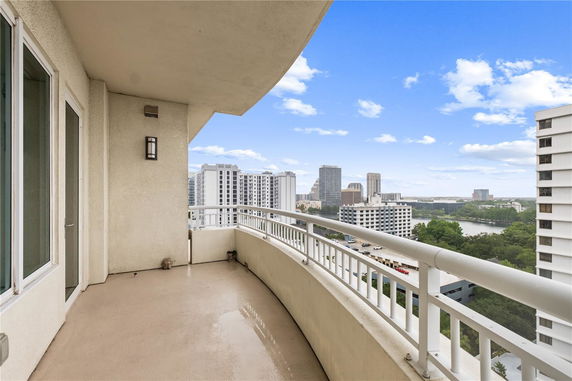 Balcony view from an upper floor of a city building showing surrounding skyscrapers and a river.