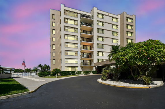 Front view of a multi-story residential building with balconies and entrance driveway.