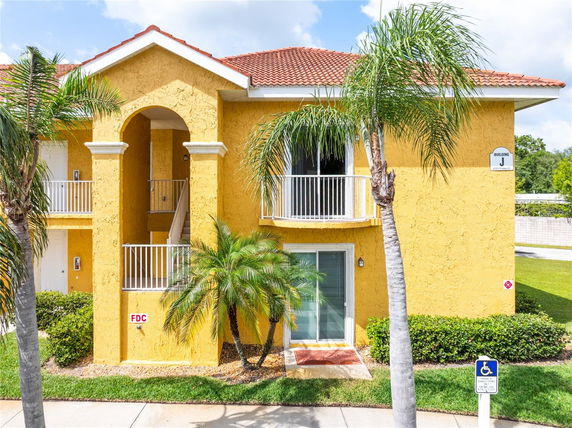 Front view of a two-story building with yellow stucco exterior and red-tiled roof.
