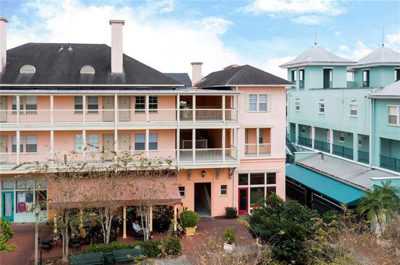 Front view of a multi-story building with balconies and several entrances at the ground level.