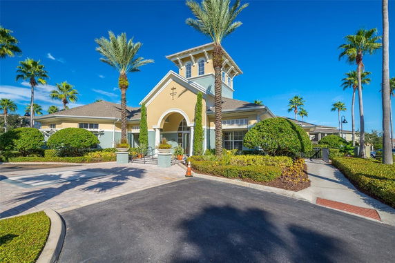 Front view of a large building with a tower, arched entrance, and surrounding landscaping.