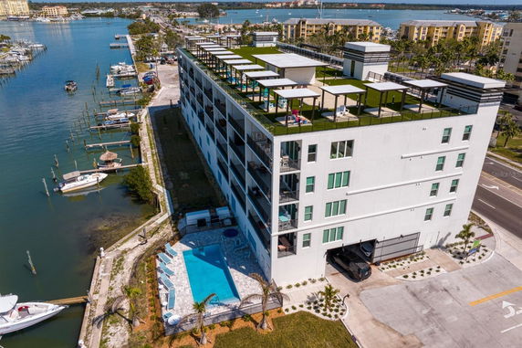 Aerial view of a multi-story building with a rooftop terrace overlooking a waterfront and nearby buildings.