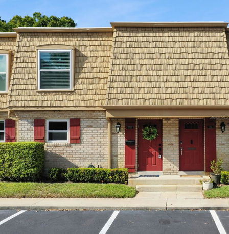 Front view of a two-story townhouse with red doors and beige brick walls.