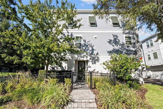 Front view of a three-story house with a path leading to the entrance.