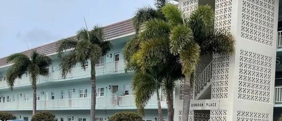 Front view of a multi-story residential building with a decorative facade and palm trees.