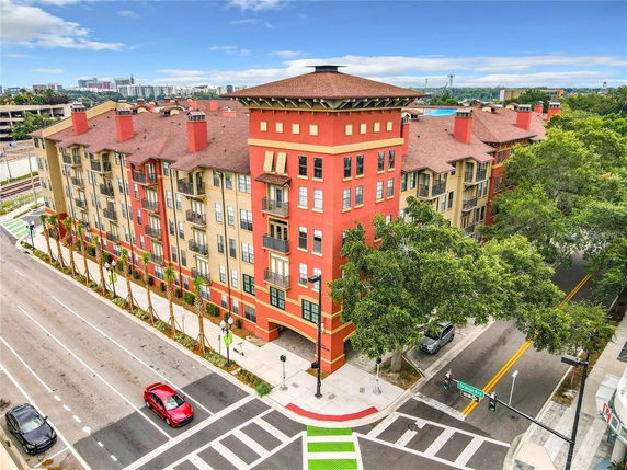 Front view of a multi-story apartment building with red and beige exterior and multiple balconies.