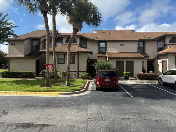 Front view of a townhouse building with multiple units and parking area.