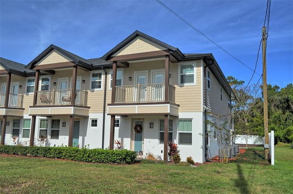 Front view of a two-story townhouse with balconies and a pitched roof.