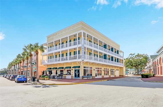 Front view of a three-story building with balconies and ground-level shops.