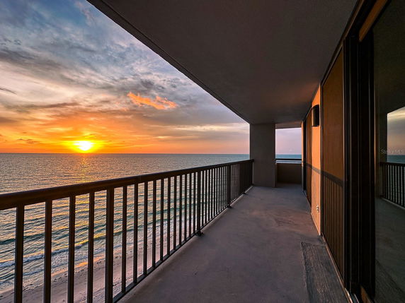 Balcony view overlooking the ocean at sunset.