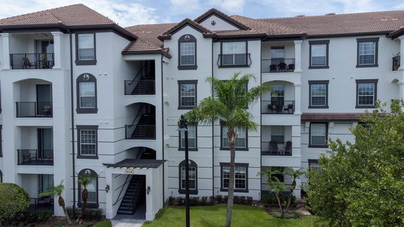 Front view of a multi-story residential building with balconies and a tiled roof.