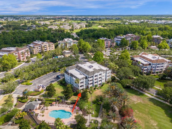 Panoramic view of residential buildings with surrounding greenery and a swimming pool.