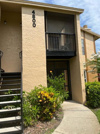 Front view of a two-story building with an exterior staircase and balcony.