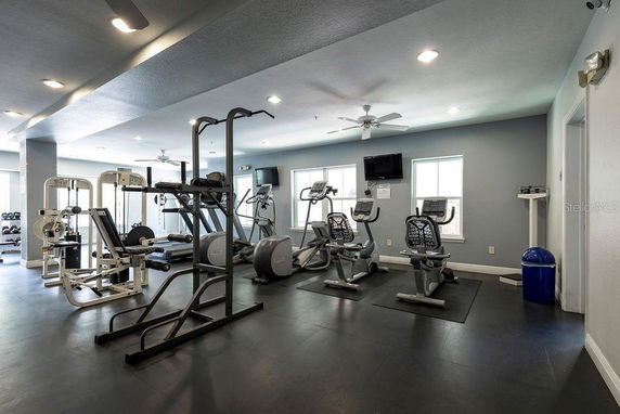 Interior view of a gym with various exercise equipment including treadmills, exercise bikes, and strength training machines.