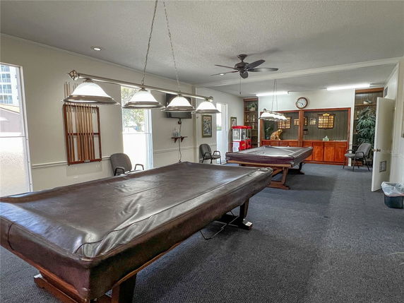 Room with multiple pool tables, chairs, and wall-mounted cue rack.