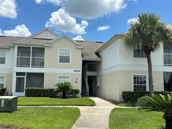 Front view of a two-story residential building with balconies and a pathway leading to the entrance.