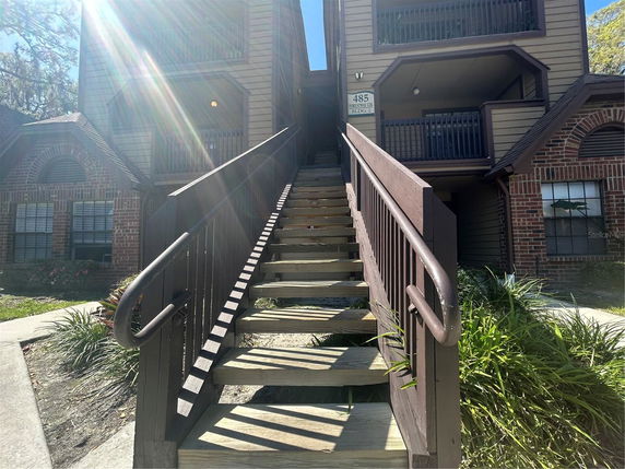 Front view of a multi-story building with wooden stairs and brick accents.