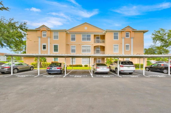 Front view of a three-story residential building with a covered parking area.