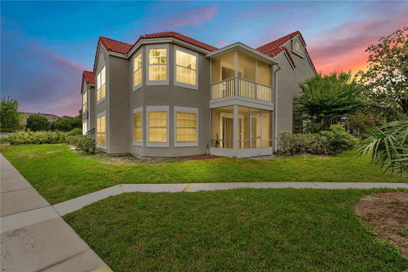 Front view of a two-story house with bay windows and a screened balcony.
