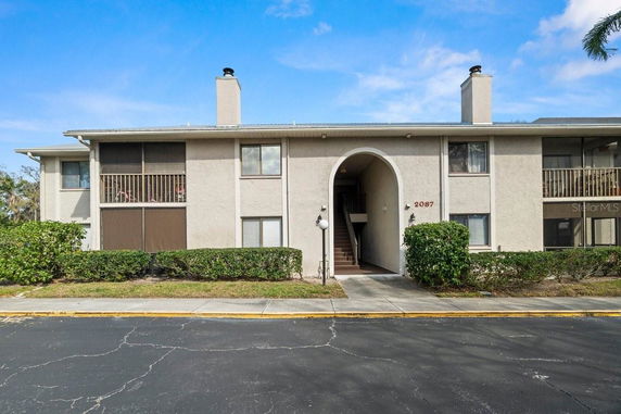 Front view of a two-story apartment building with an arched entrance and balconies.