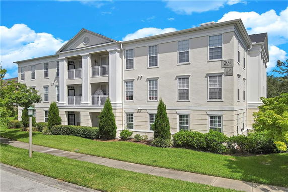 Front view of a three-story apartment building with columns and balconies.