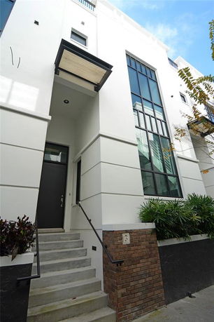 Front view of a modern multi-story building with a large glass window and brick accents.