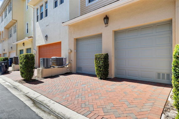 Front view of townhouses with garage doors and exterior lighting.