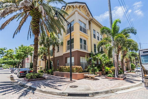 Front view of a multi-story building with palm trees and surrounding sidewalk.