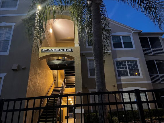 Front view of a multi-story building with an entrance staircase and balconies.