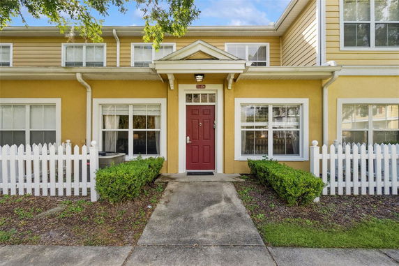 Front view of a two-story house with yellow siding and a red door.