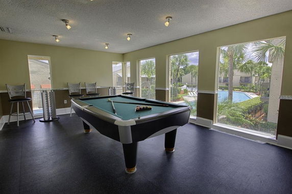 Room with a pool table and large windows.