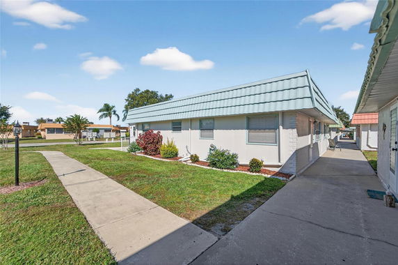 Front view of a single-story house with a light blue roof and landscaped yard.