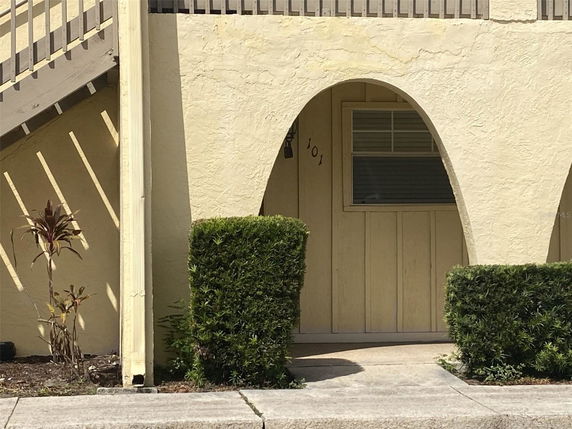 Front view of a building with arched entryway and textured stucco exterior.