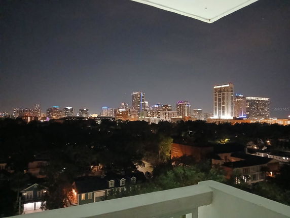 Nighttime panoramic cityscape view from a building balcony.