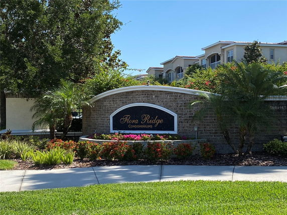 Front view of condominium entrance with a sign and landscaped garden.