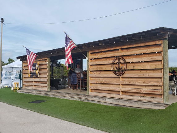 Front view of a wooden outdoor pavilion with flags and seating.