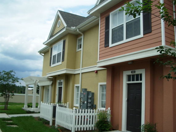 Front view of a two-story house with beige and orange exterior, featuring white trim and dark doors.