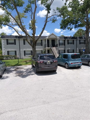 Front view of a two-story residential building with a central staircase and parking area in front.