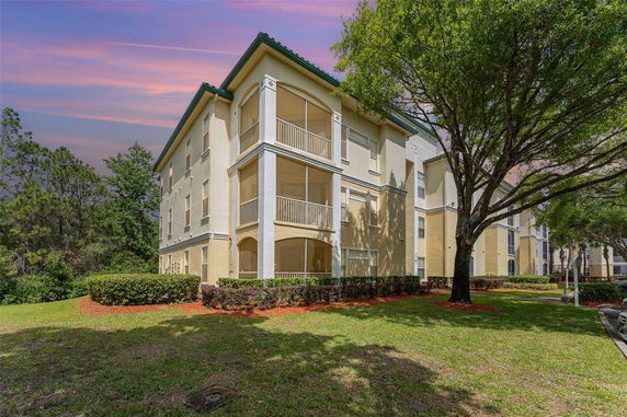 Front view of a multi-story residential building with screened balconies and beige exterior.