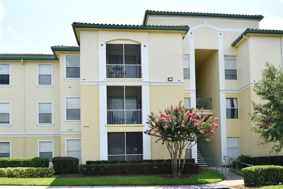 Front view of a multi-story yellow apartment building with balconies.