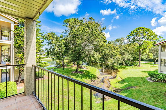 View of lush greenery and a small water body from a balcony.
