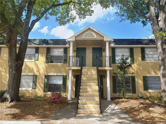Front view of a two-story building with stairs leading to an upper entrance.