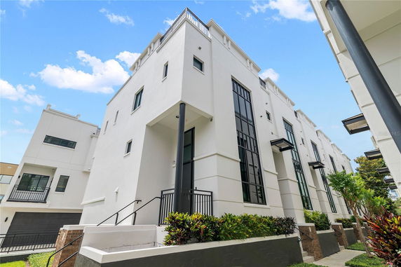 Front view of a modern multi-story building with large windows and a clean, white facade.